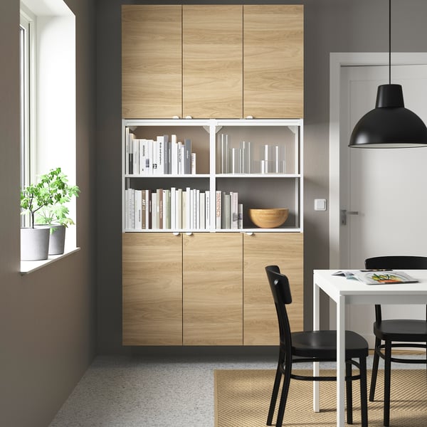 ENHET storage with light wood, white shelf, and decor. Black dining set, plant.