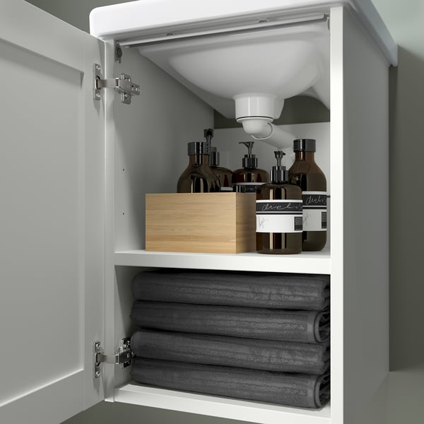 Open bathroom cabinet with rolled towels and bottles, showcasing storage and organization.