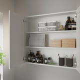 White wall cabinet, fully open showing organized shelves with bottles, storage bins, and clutter-free design.