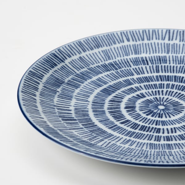 Circular blue-white patterned plate, intricate radial designs, slight texture.