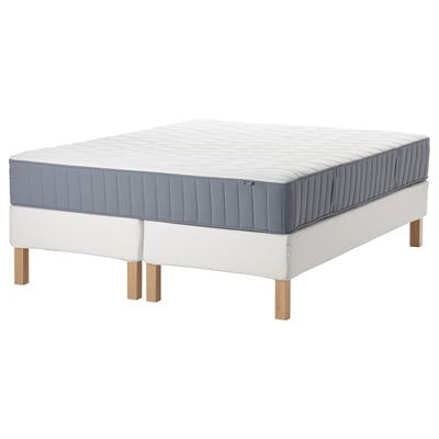 Sleep mattress on white base, blue-gray top, wooden legs, square shape.