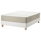 Shows a rectangular, white mattress with wooden legs and quilted design, showing base support.