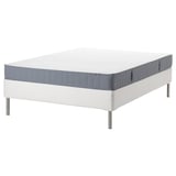IKEA white bed frame with blue-gray mattress, metal legs.