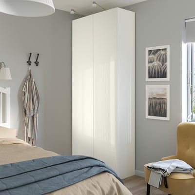 A modern bedroom with a tall, sleek FARDAL wardrobe in white gloss finish, larger than the nearby yellow chair, against a grey wall.
