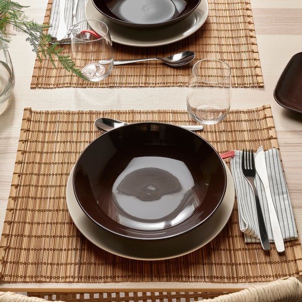 Table set with FÄRGKLAR deep plates, utensils, and glassware on bamboo mats.