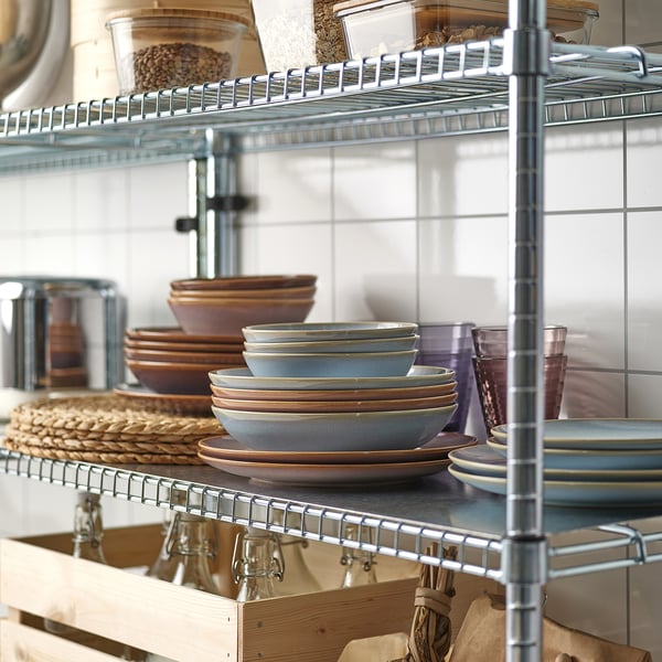 Wire shelves in kitchen storing plates, bowls, cups, and jars; organized and accessible.