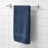 FREDRIKSJÖN blue towel hangs on wall rack, soft cotton, rectangular with decorative border.