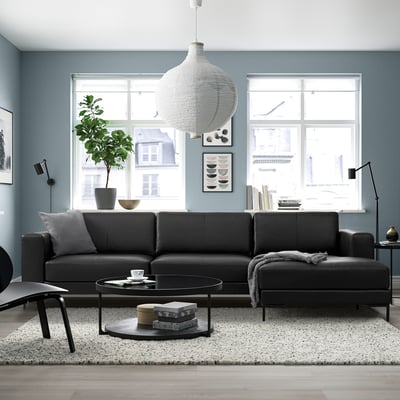 Modern living room with FULLERÖ black leather 3-seat sofa, round coffee table, large windows, and hanging lamp.