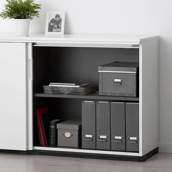 White GALANT cabinet with 2 shelves, combo lock, gray boxes, files, plant, photo.