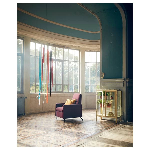 Chair with colorful ribbons, large windows, arched green ceiling, fireplace, and glass cabinet.