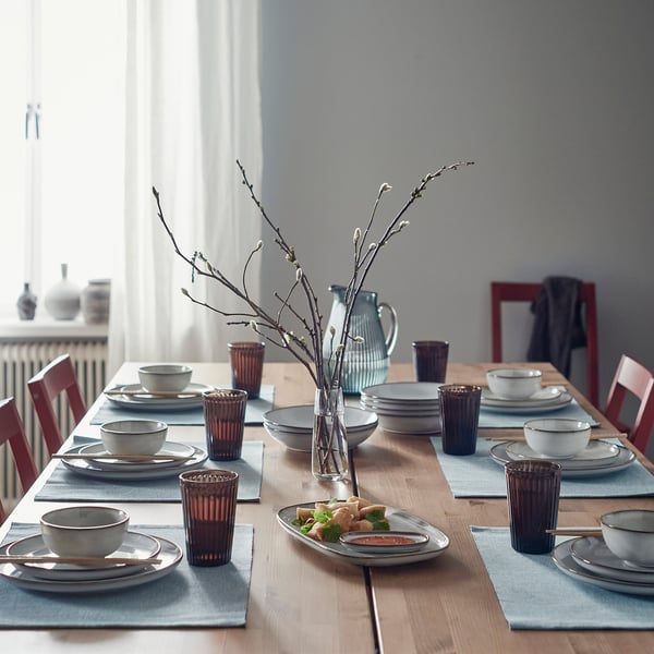 Glazed GLADELIG bowl on table with plates and cups, handcrafted, classic shape.
