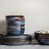 Ceramic bowls, ocean blue with gold rim, stacked neatly on table, decorative, handcrafted look.