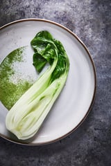 GLADELIG white plate with green leafy vegetable, light glaze, stoneware, round shape, minimal design.