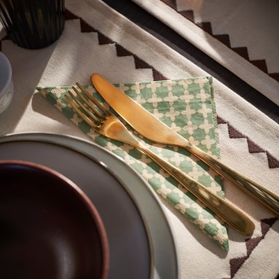 A stack of green and white patterned gokvallå napkins, made of paper, neatly folded.
