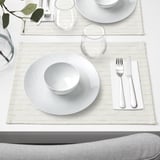 White porcelain table setting with plate, bowl, glass, cutlery, and napkin. Geometric design, arranged neatly.