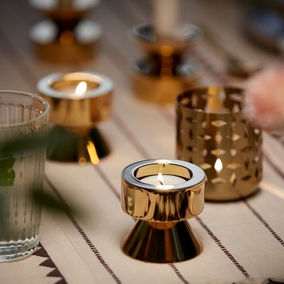 Six silver tealights, cylindrical with wicks, arranged in a circular pattern, gleaming metal reflecting light.