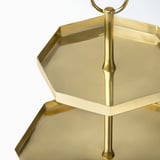 Gold-colored, two-tiered octagonal serving stand. Shiny, sleek design with carrying handle, exudes elegance.