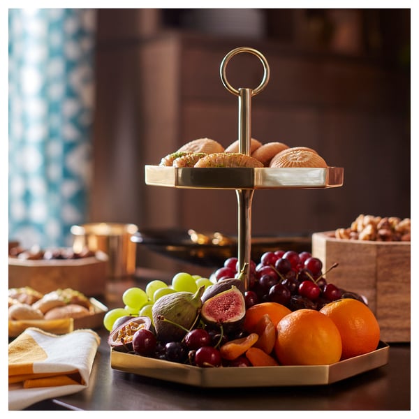 Gold-colored gokvallå 2-tier serving stand with fruits and pastries. Octagonal, metallic design with a central handle.