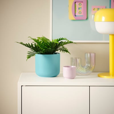 GRADVIS light blue planter holds green fern; sits on white shelf next to pink & multi-colored vases, yellow lamp.