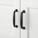 Two black handles on white cabinet doors. Smooth finish, sleek design, modern aesthetic.