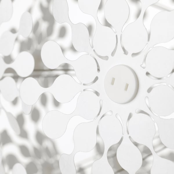 White lamp casts intricate shadows on a wall, elegant both on and off.