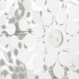 White lamp casts intricate shadows on a wall, elegant both on and off.