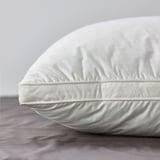 Pillow with smooth cotton cover and supportive core, resting on bed.