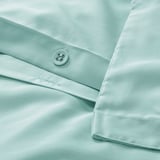 Close-up of turquoise duvet set button; shows smooth fabric and elegant piping.