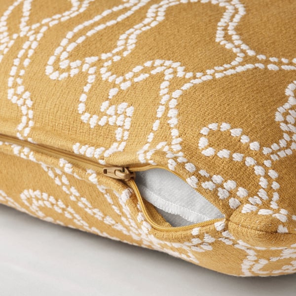 A yellow cushion cover with a white pattern, partially unzipped to reveal its function.