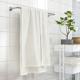 GULVIAL towel, beige, 100% cotton, medium-thick, soft, folded on holder, near white shelves.