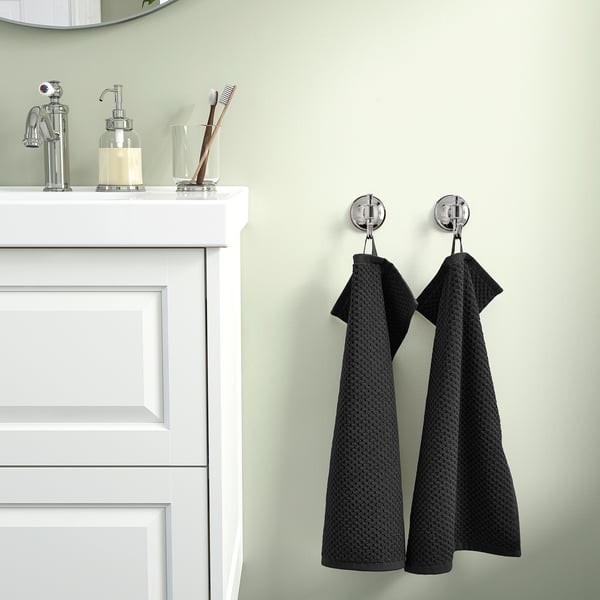 Two towels hang on hooks beside a white sink cabinet.