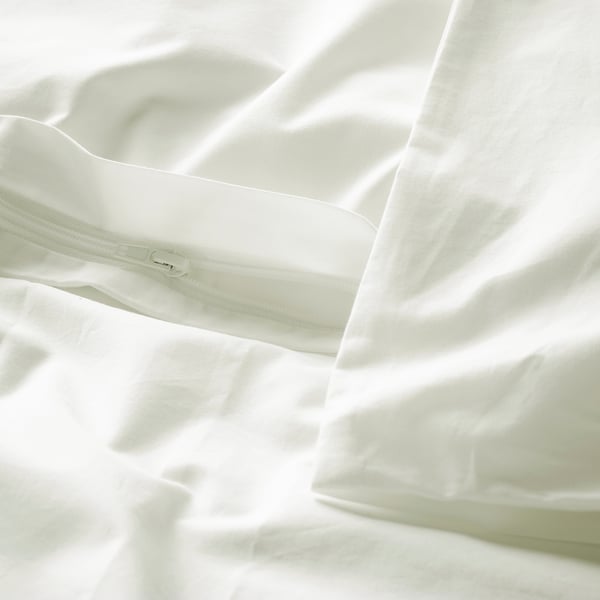 Close-up of white bed linen with zipper detail on pillowcase, showcasing crisp cotton texture.