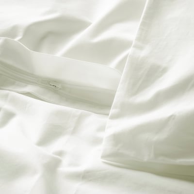 Close-up of white bed linen with zip detail on pillowcase, showcasing crisp cotton texture.