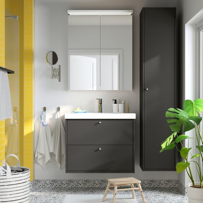 Modern bathroom with HAVBÄCK grey vanity, large mirror, black cabinet, green plant, and yellow tiles.