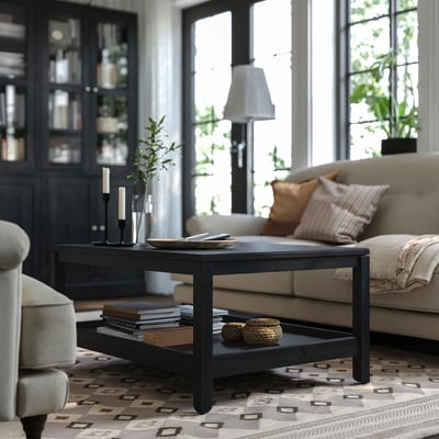 Living room with beige sofa, patterned rug, black HAVSTA coffee table, and large windows.