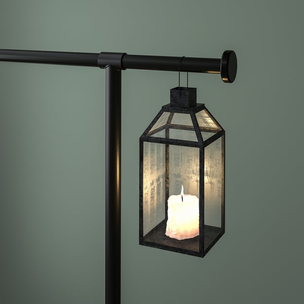 A hanging lantern with a lit candle inside, suspended from a decorative rod clamped to a table.