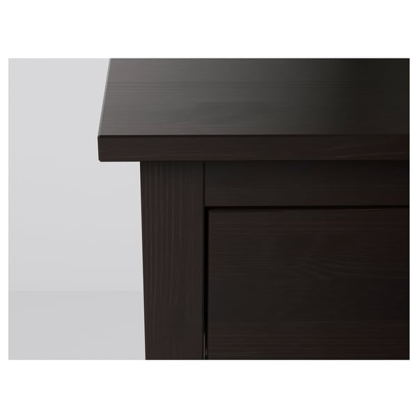 Dark wood chest of drawers corner close-up, smooth finish, sturdy construction.