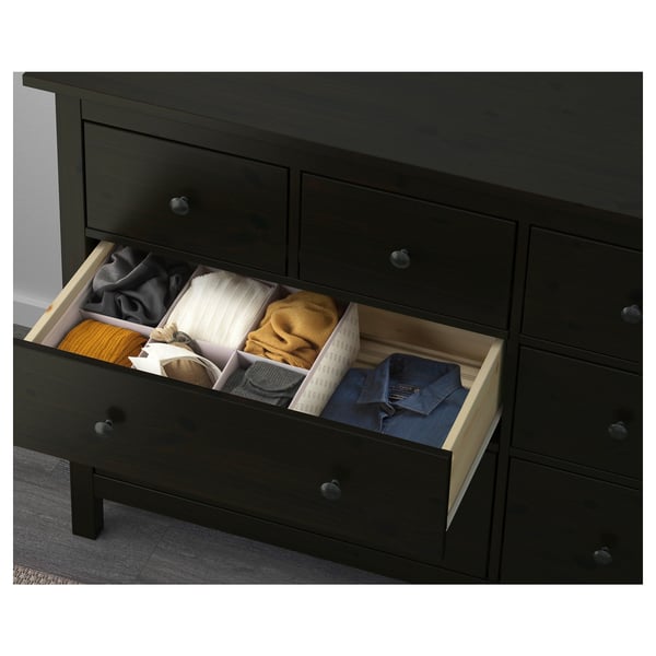 Black wooden dresser with six drawers, one open showing color-coded clothing, smooth drawer runners evident.