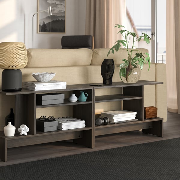 Dark brown HOLMERUD side table with shelves beside yellow sofa, blending modern design.