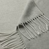 Soft grey-green woven throw with fringed edges, made from recycled polyester, draped to show texture.