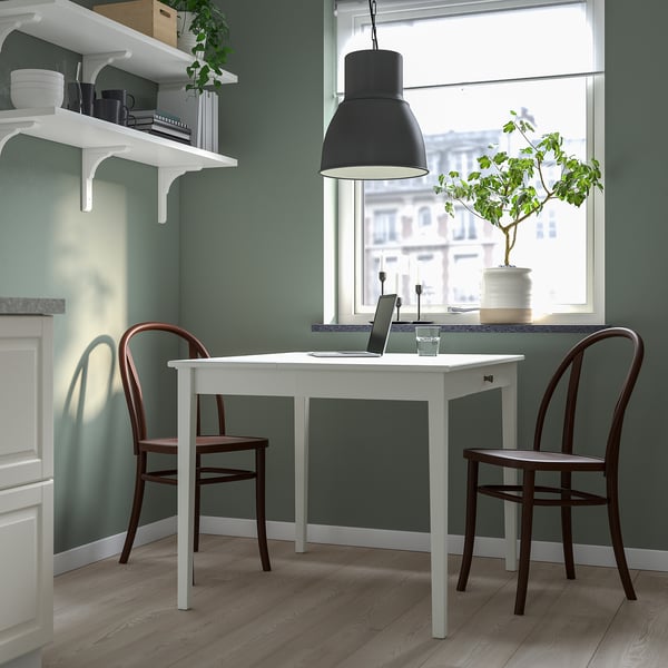 Modern compact home office with white drop-leaf table and brown chairs, green walls, and large window.