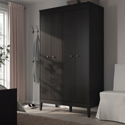 Modern bedroom with dark IDANÄS wardrobe, two closet doors, near window, chair, and rug.