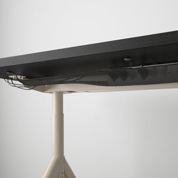 Desk with adjustable metal legs securing cables underneath.