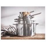 Stack of stainless steel pots and pans, one holding noodles. Shiny, sleek ikea design, suitable for any stove.
