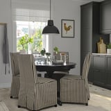 Modern black dining set with striped chairs, extendable table, dark cabinets, and rooster painting.