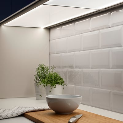 Modern kitchen setup with undershelf lighting, plants, and a bowl on the countertop.