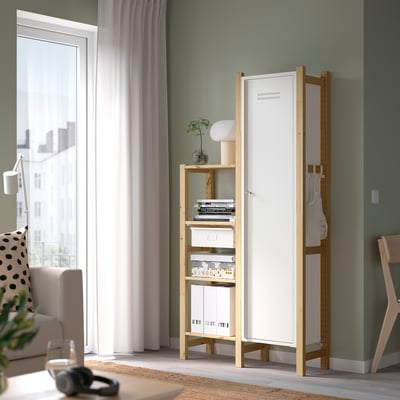 White IVAR cabinet by window, with books & lamp. Steel & pine, modern minimalist decor.