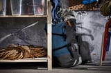 IVAR storage shelf with gray backpack, coiled rope, and clear bin.