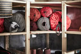 IVAR wooden shelves stock red bags, coiled rope, gray sandbags, black boots.