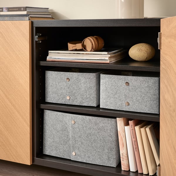 Shelf displaying organized books, storage boxes, headphones, and decor items.